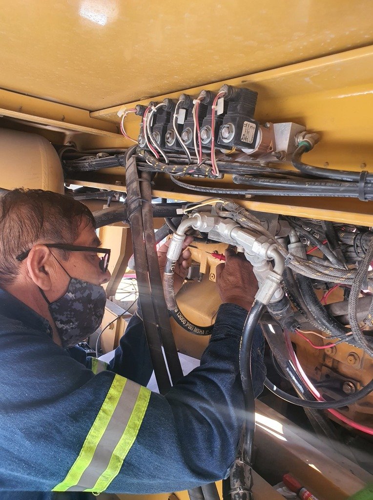 Técnico MIM realizando mantenimiento en sistema hidráulico de maquinaria industrial